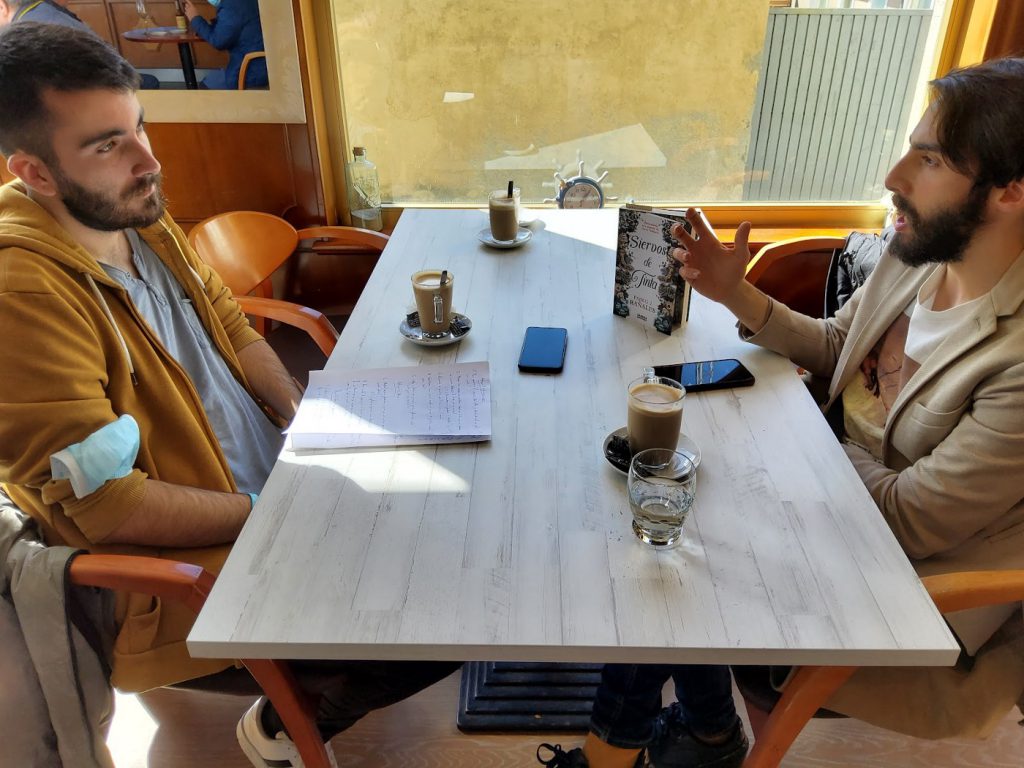 Pablo J. Rañales en diálogo con el periodista Jorge Rivero sobre su primera novela, Siervos de Tinta, en una cafetería de Ares